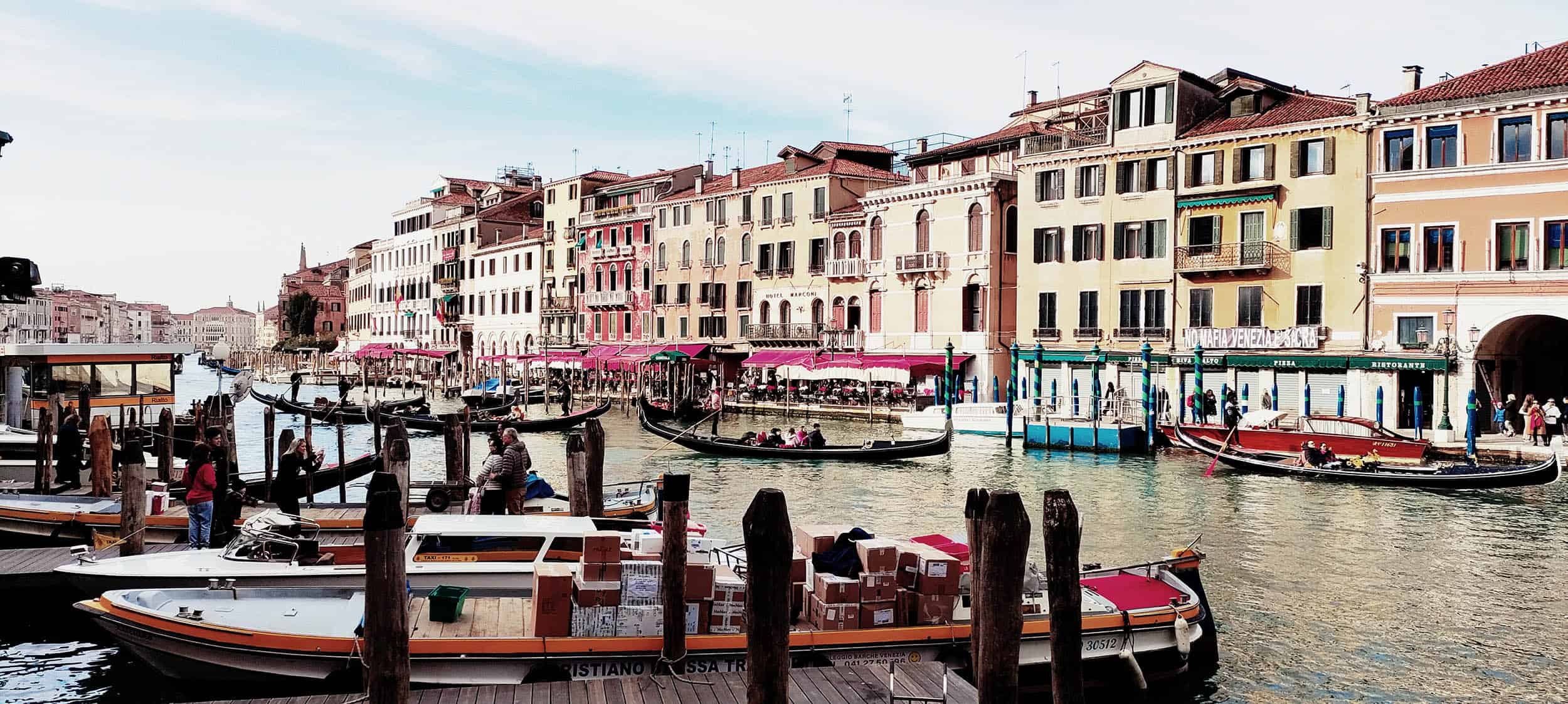 Kanal og brygge i Venezia omkranset av turister