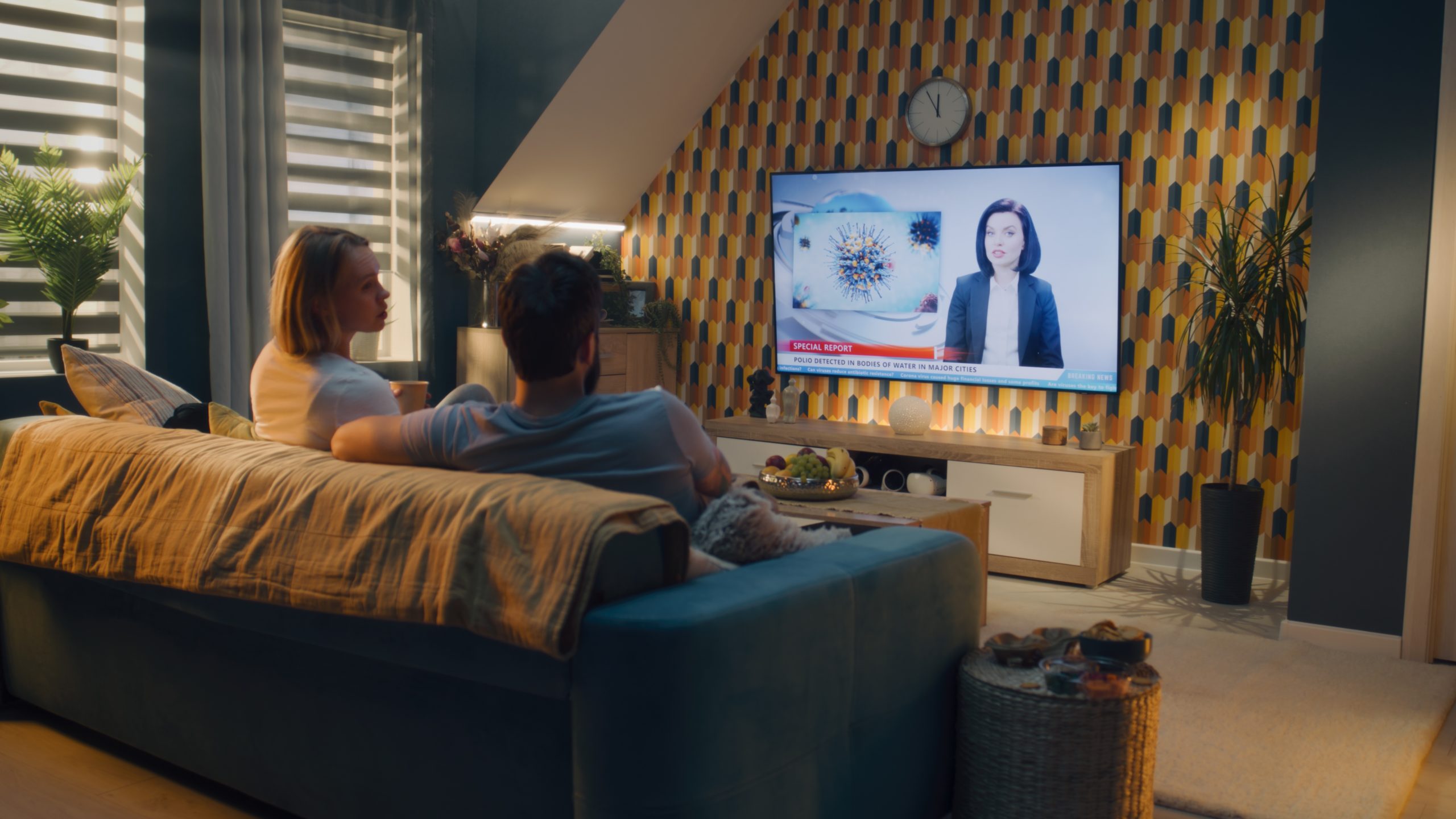 Couple,Sitting,On,Sofa,In,Living,Room,,Talking,,Watching,Tv