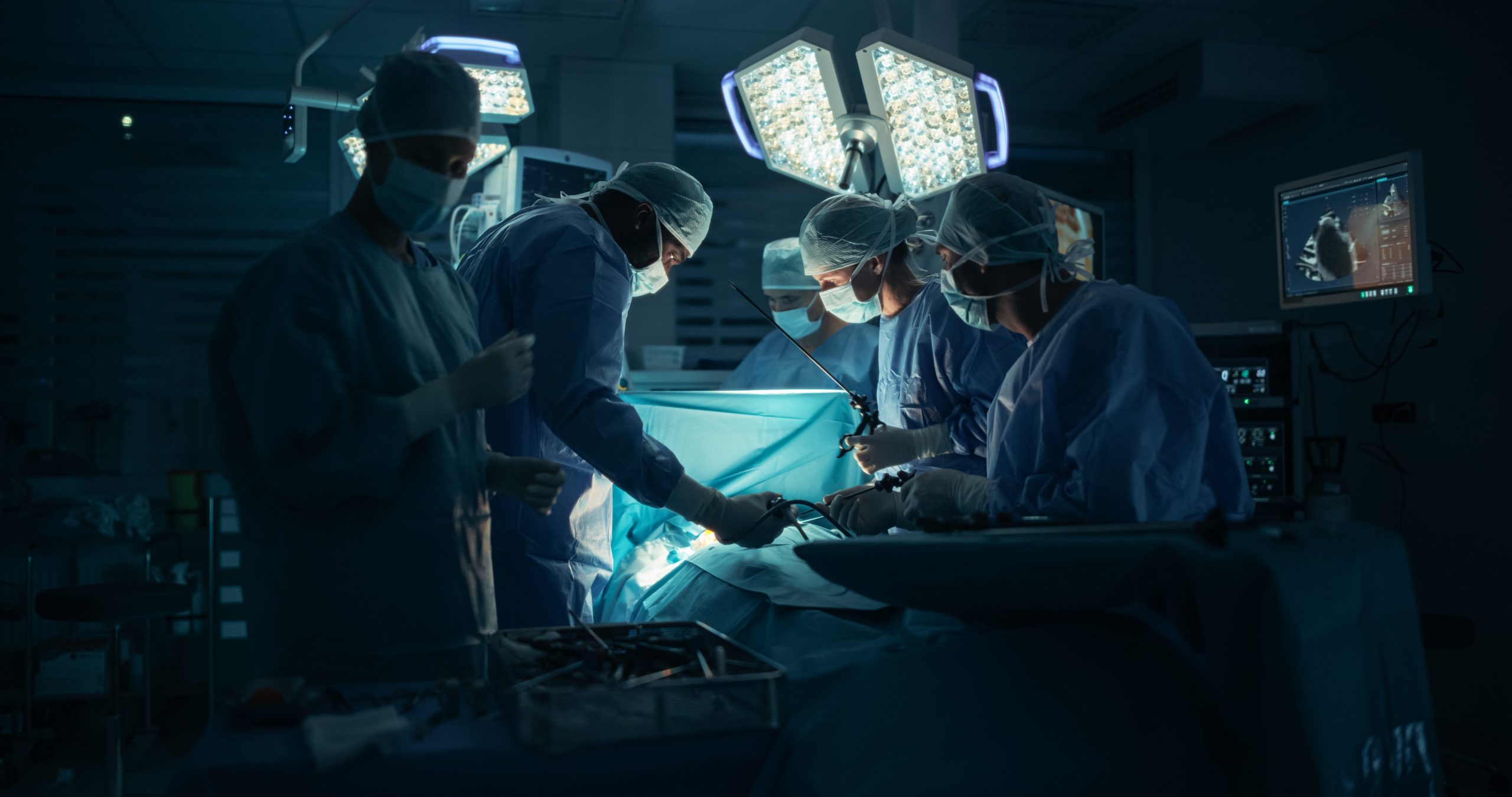 Diverse,Surgical,Team,Working,In,A,Darkened,Operating,Room,Surrounded